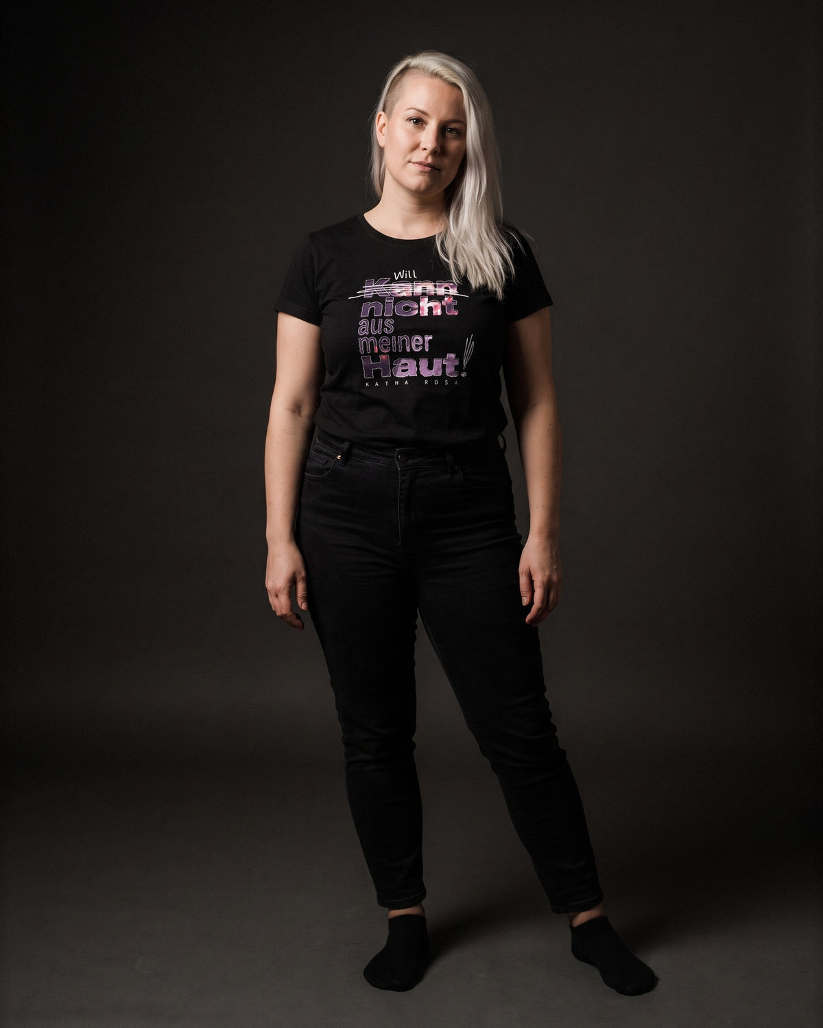 Frau mit platinblonden Haaren im schwarzen Kann nicht aus meiner Haut T-Shirt tailliert